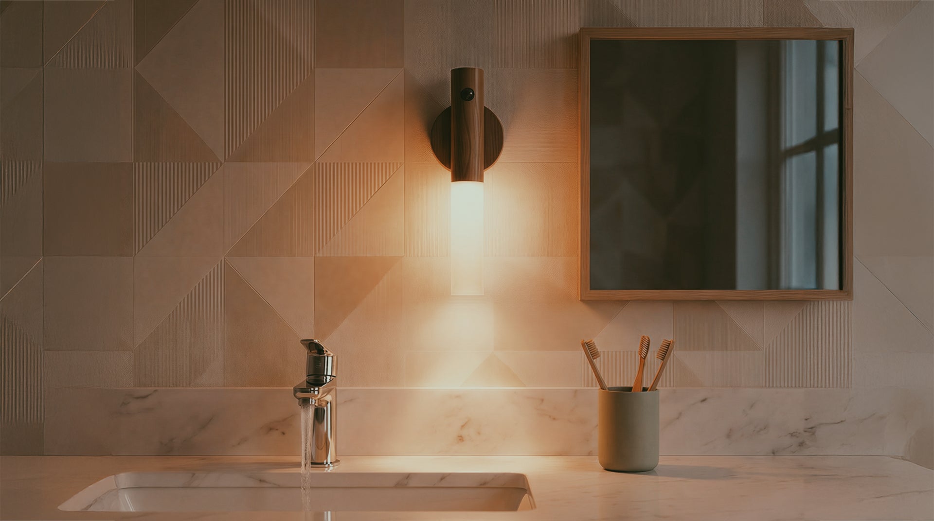 Bathroom sink area with geometric wall tiles, with a portable light fixture, and mirror.